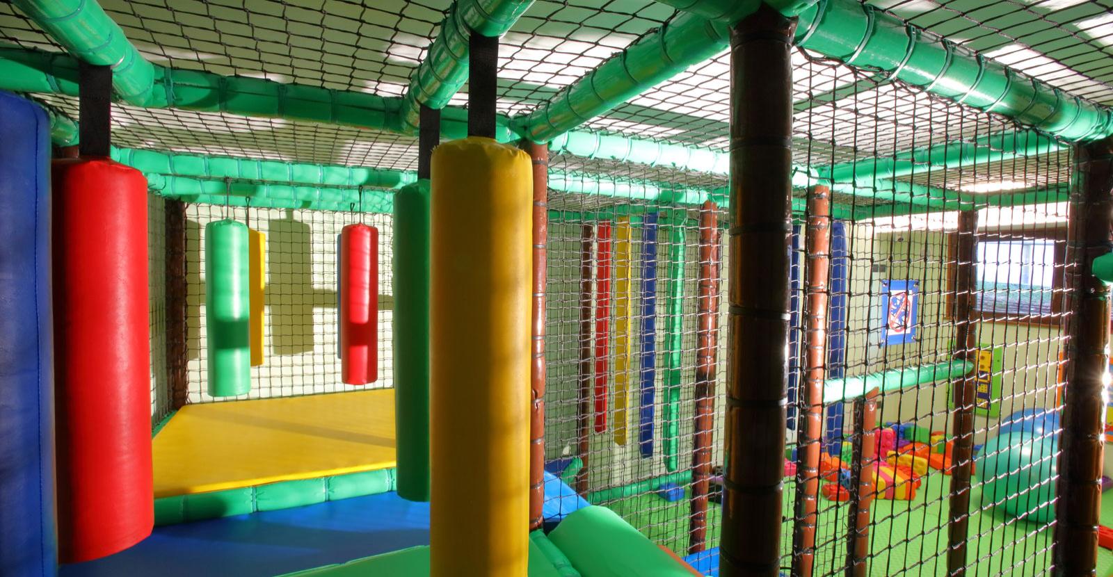 Children's play area with colorful obstacles and safety nets.