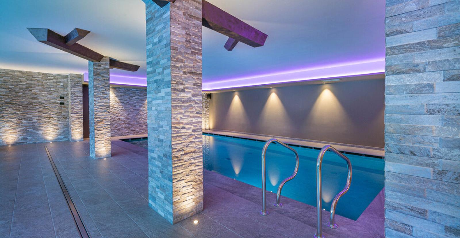 Indoor pool with soft lighting and stone columns.
