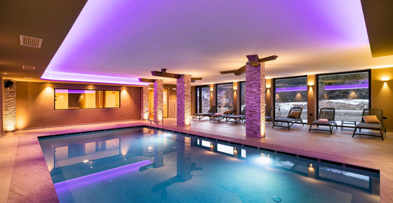 Indoor pool with soft lighting and lounge chairs for relaxation.