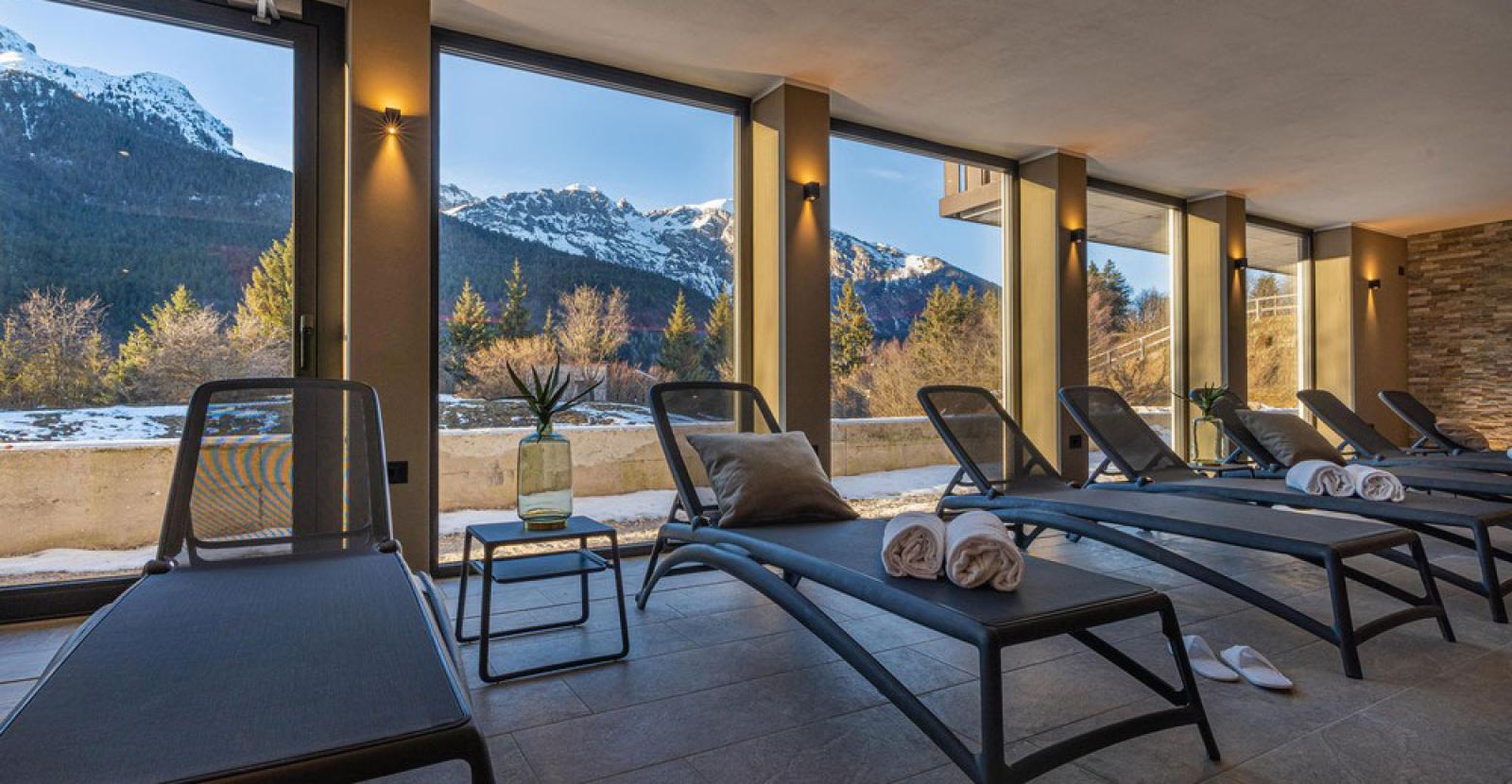 Relaxation room with mountain view, loungers, and rolled towels.
