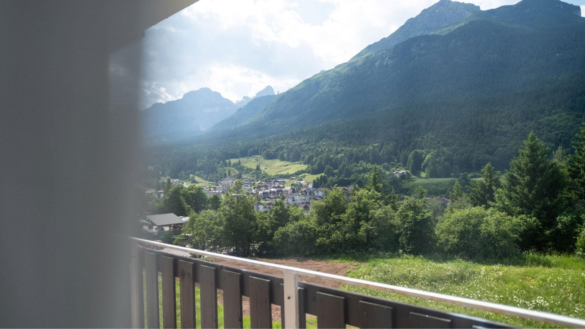 Panoramic view of a mountain valley with houses and lush vegetation.