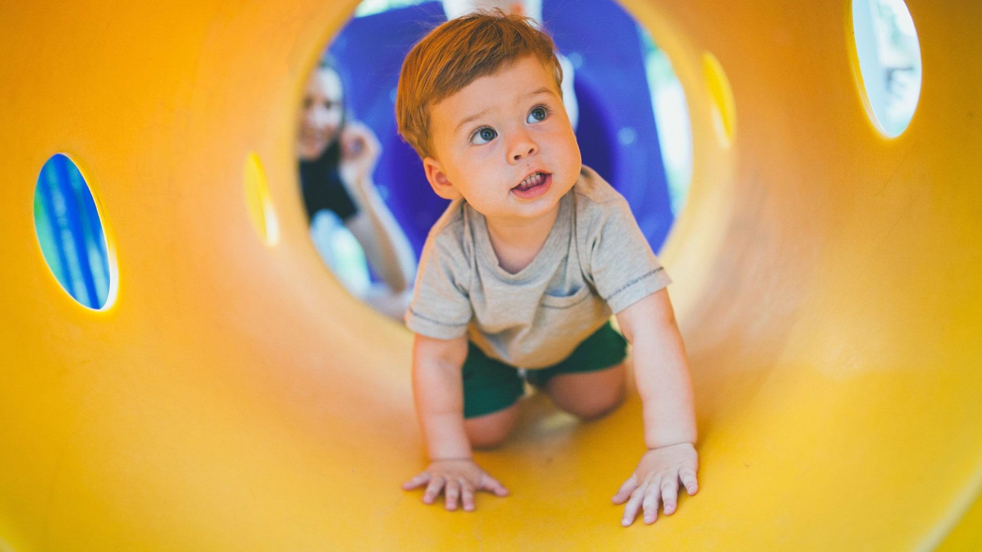 Child playing in a colorful tunnel at the playground.