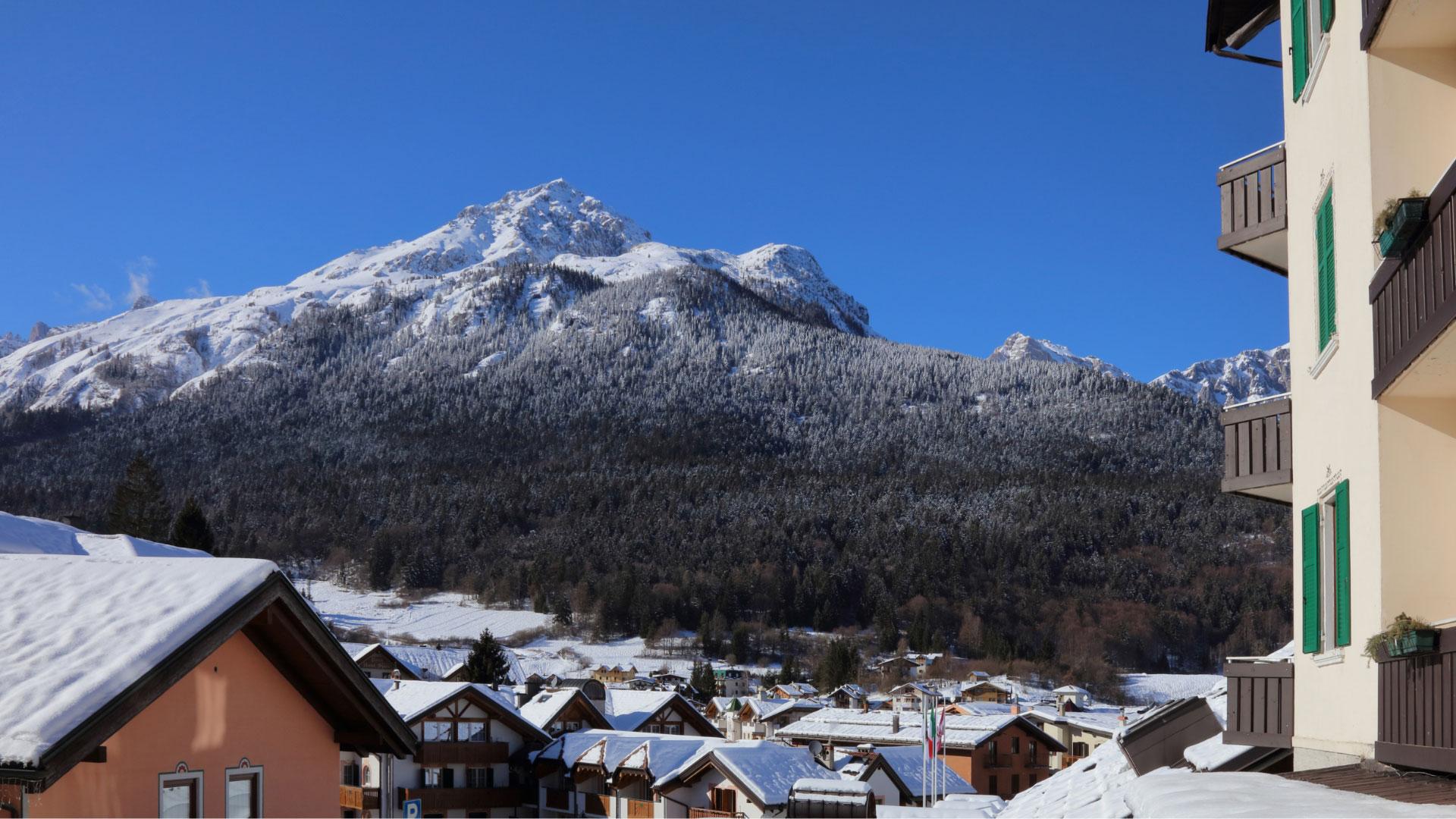 View of a snowy mountain village with mountains in the background.