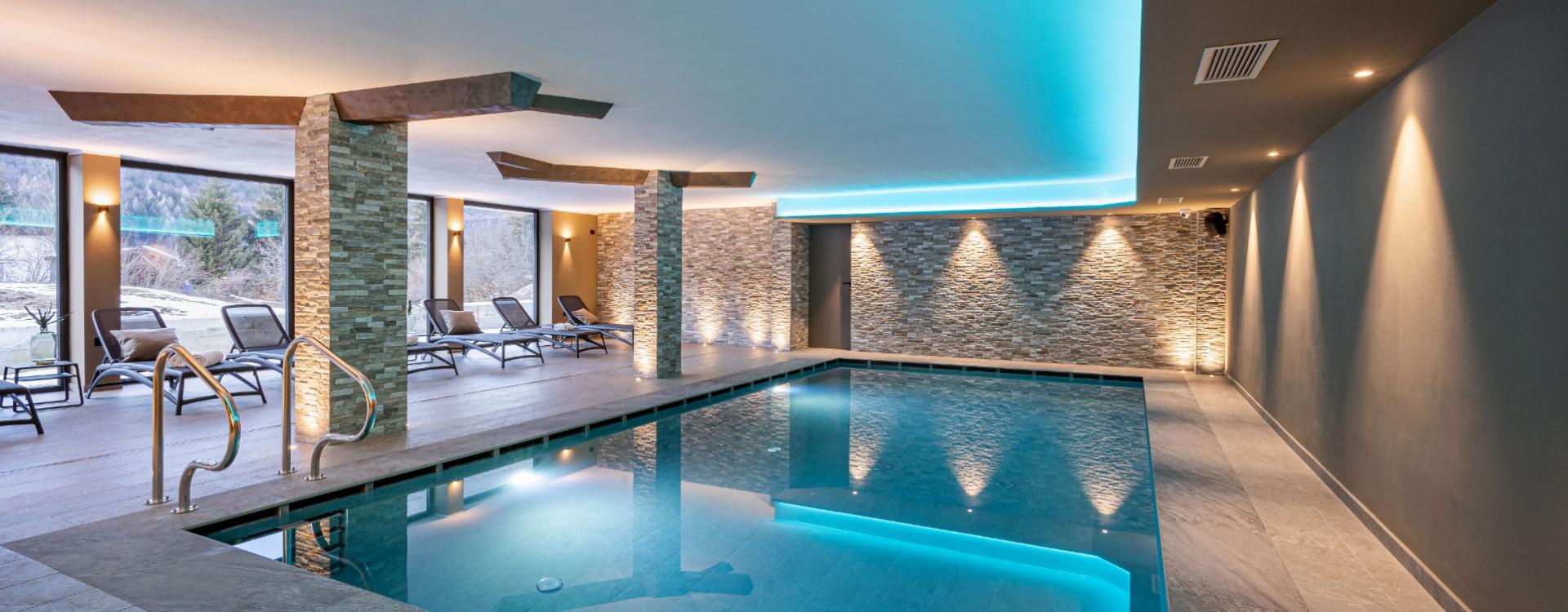 Indoor pool with soft lighting and lounge chairs.
