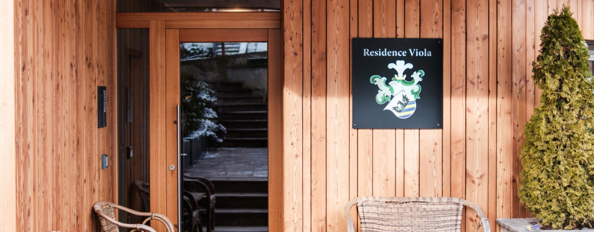 Entrance of Residence Viola with wooden walls and decorative plants.