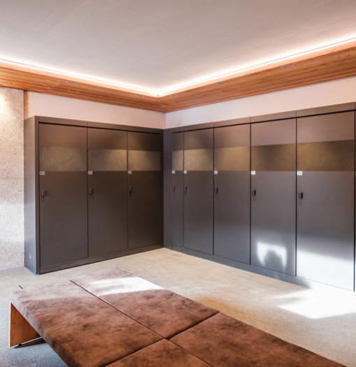 Modern locker room with dark lockers and padded bench.