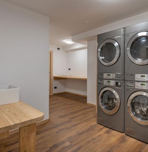 Modern laundry room with stacked washers and wooden floor.