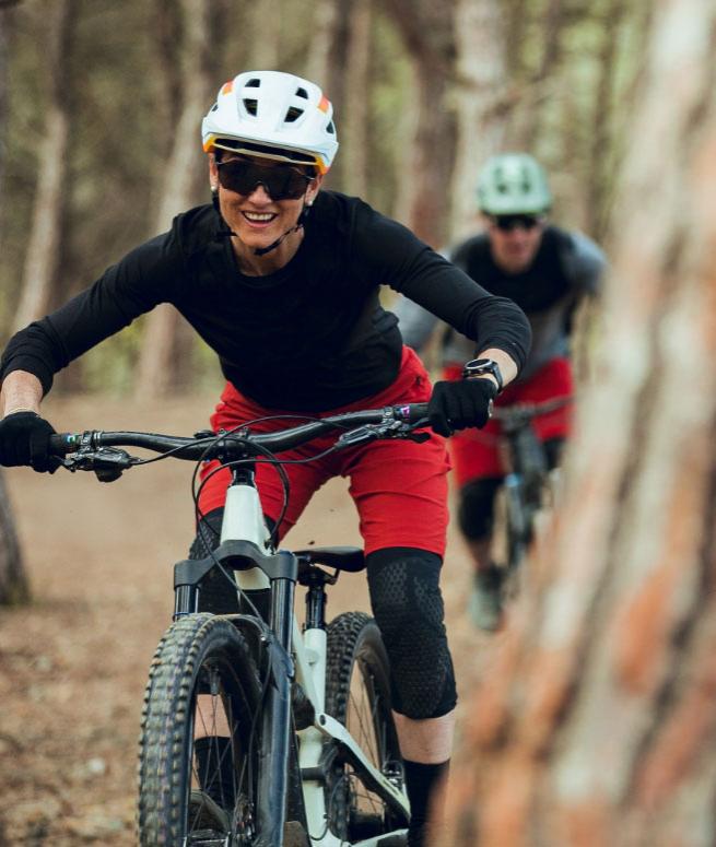 Two mountain bikers ride on a forest trail.