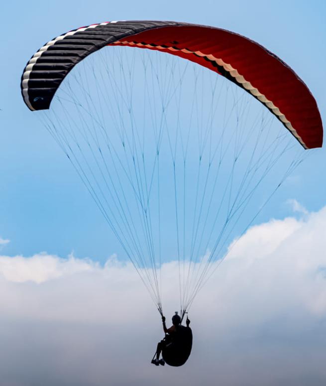Persona che fa parapendio sotto un cielo azzurro con alcune nuvole.