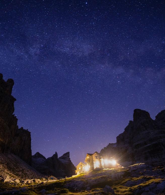 Rifugio di montagna illuminato sotto un cielo stellato.